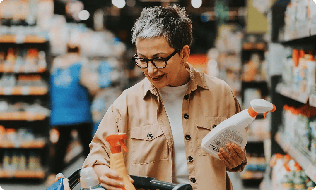 Shopper comparing cleaning product packaging and labels in a retail store