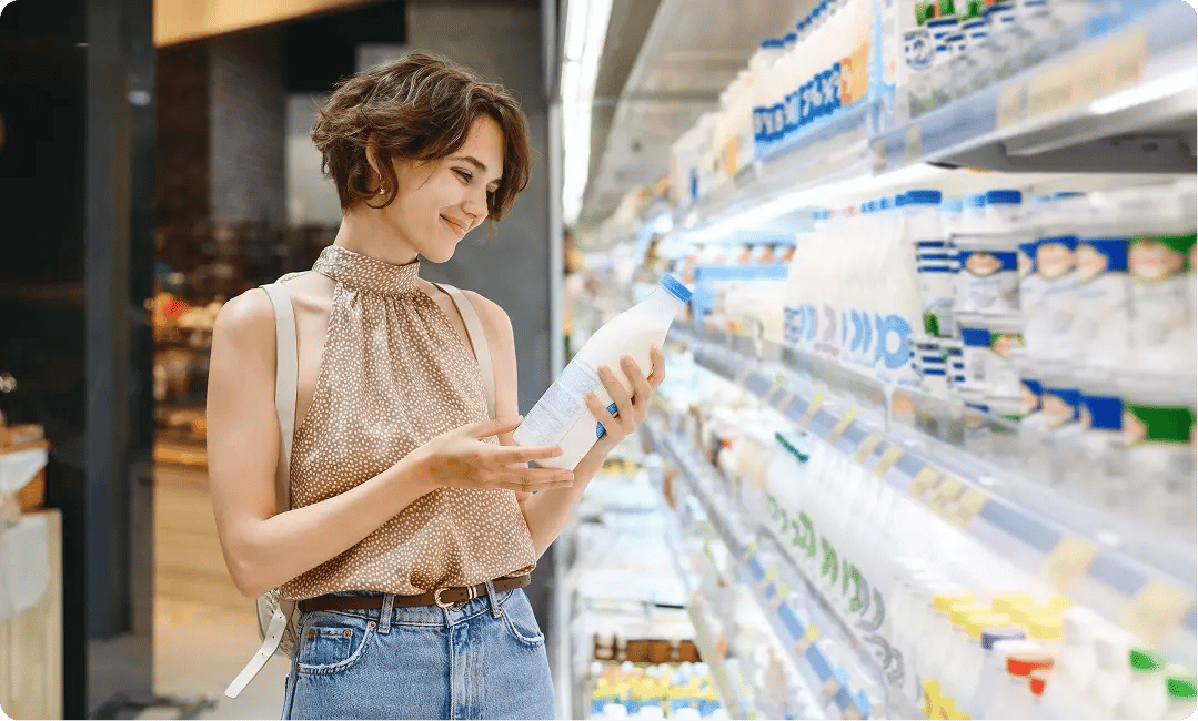 Shopper reviewing dairy product packaging in a supermarket aisle