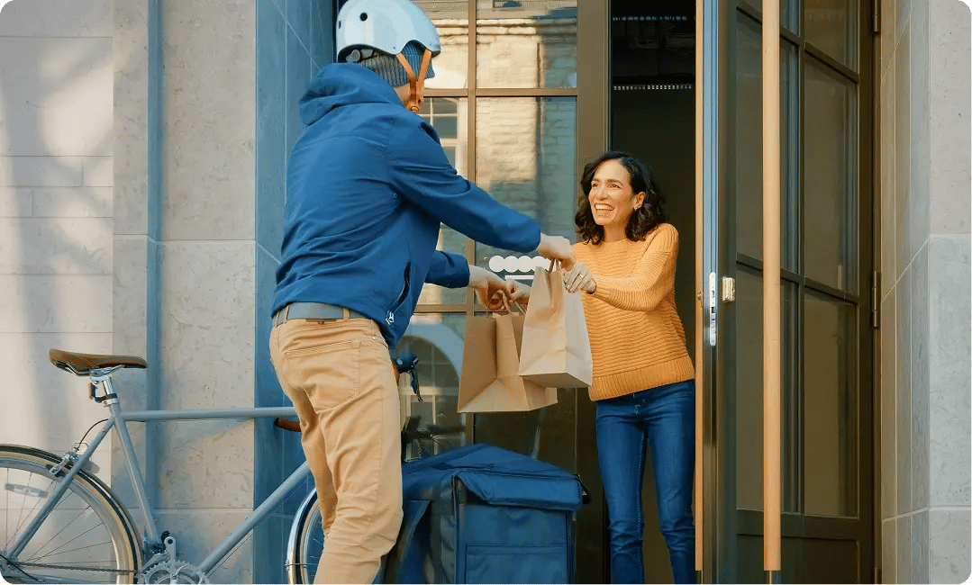Grocery delivery courier handing a box of fresh produce to a customer